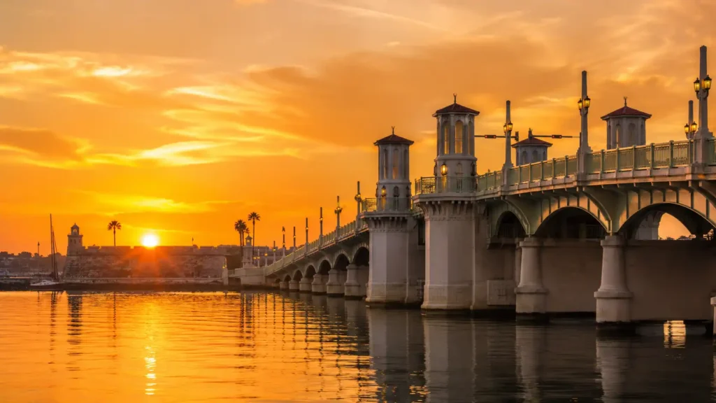 Stunning golden hour sunset view behind the historic Castillo de San Marcos and the Bridge of Lions in St. Augustine, Florida.