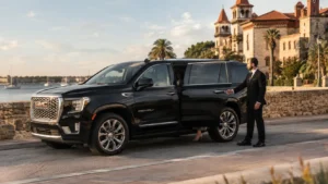 A luxury black GMC Yukon SUV parked elegantly along the historic bayfront avenue in St. Augustine, showing a professional chauffeur opening the door for an executive passenger.